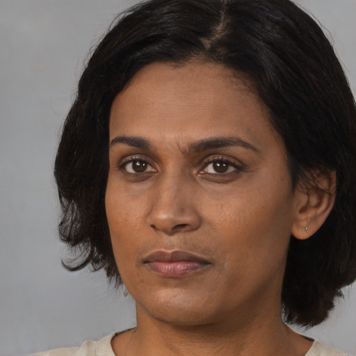 Joyful white adult female with medium  black hair and brown eyes