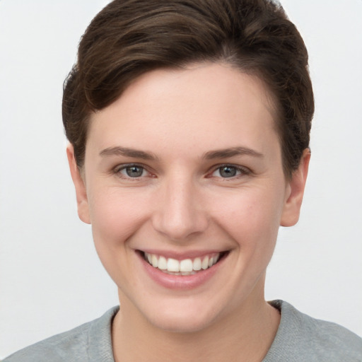 Joyful white young-adult female with short  brown hair and grey eyes