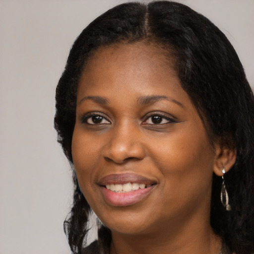 Joyful black young-adult female with long  black hair and brown eyes