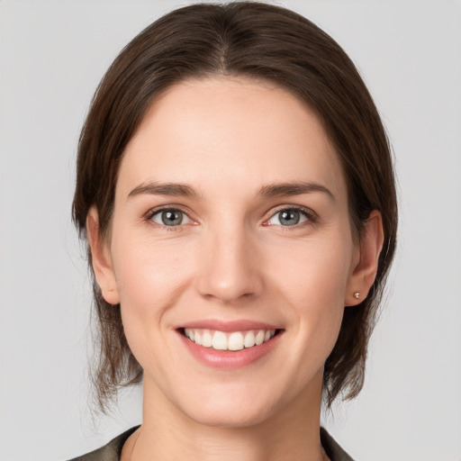 Joyful white young-adult female with medium  brown hair and grey eyes