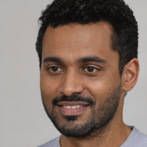 Joyful black young-adult male with short  black hair and brown eyes