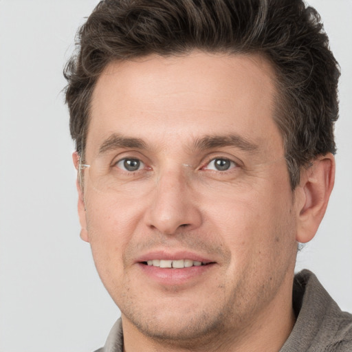 Joyful white adult male with short  brown hair and grey eyes