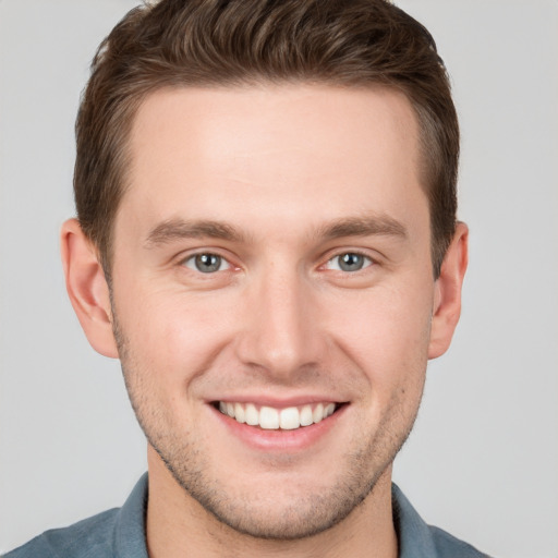 Joyful white young-adult male with short  brown hair and grey eyes