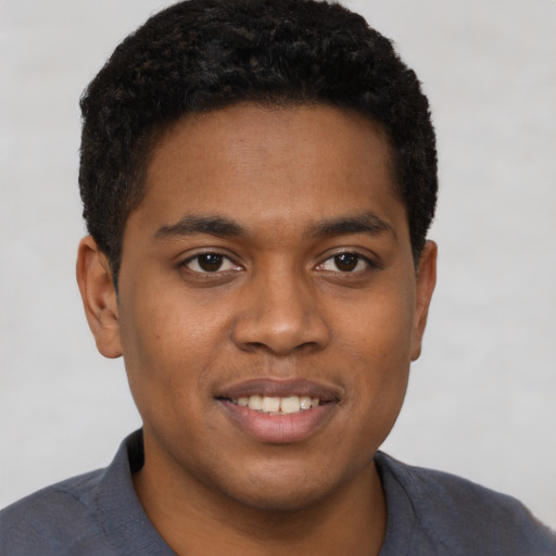 Joyful black young-adult male with short  brown hair and brown eyes