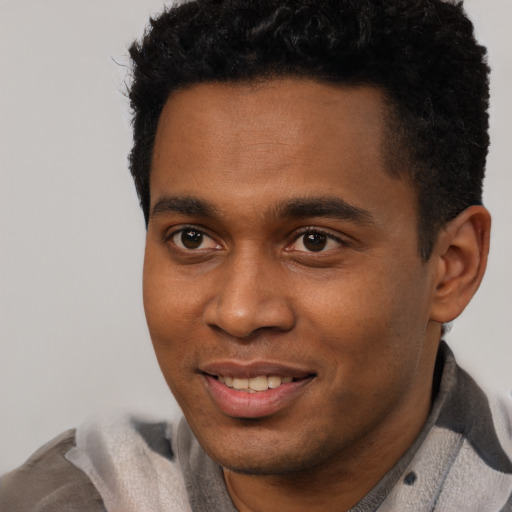 Joyful black young-adult male with short  black hair and brown eyes