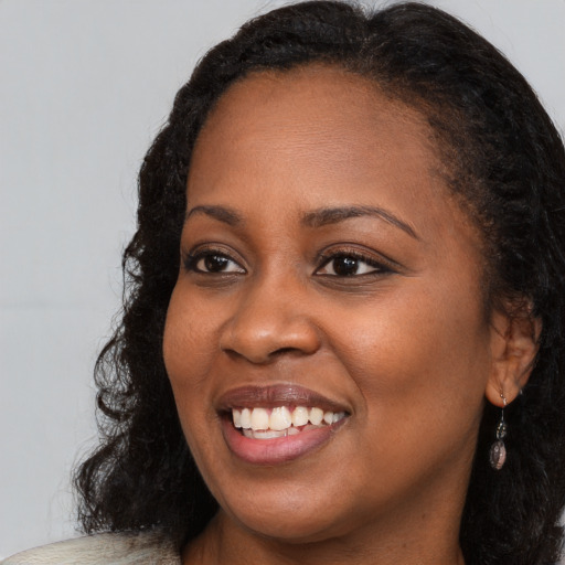 Joyful black young-adult female with long  brown hair and brown eyes