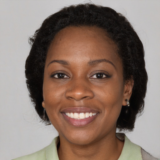 Joyful black adult female with medium  brown hair and brown eyes