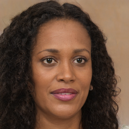 Joyful black young-adult female with long  brown hair and brown eyes