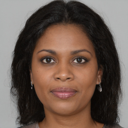 Joyful black young-adult female with long  brown hair and brown eyes