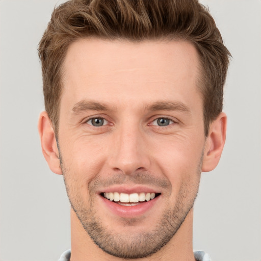 Joyful white young-adult male with short  brown hair and grey eyes