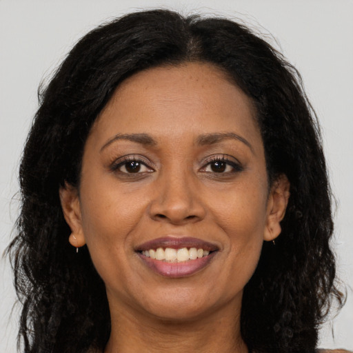 Joyful black adult female with long  brown hair and brown eyes