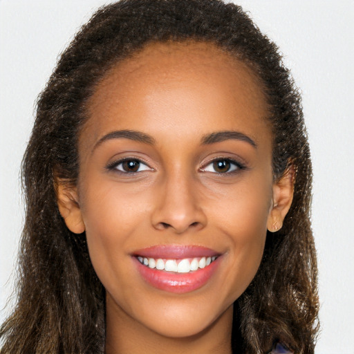 Joyful black young-adult female with long  brown hair and brown eyes