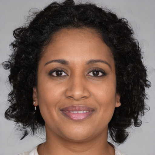 Joyful black young-adult female with long  brown hair and brown eyes