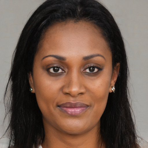 Joyful black young-adult female with long  brown hair and brown eyes