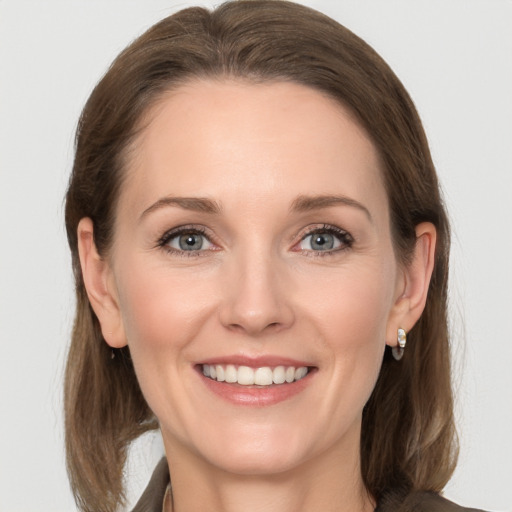 Joyful white adult female with long  brown hair and grey eyes