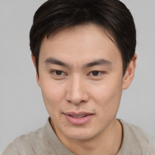 Joyful asian young-adult male with short  brown hair and brown eyes