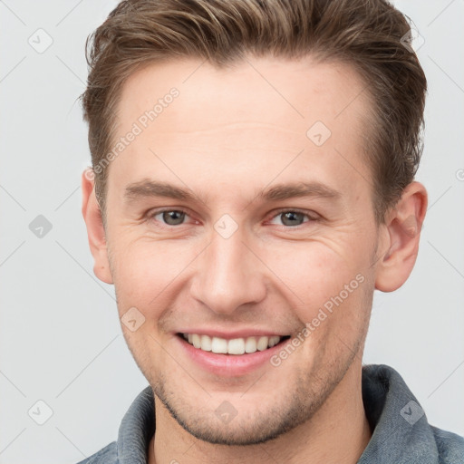 Joyful white young-adult male with short  brown hair and grey eyes