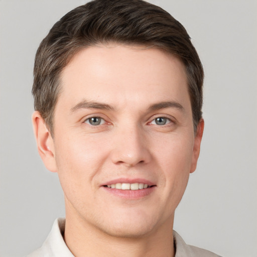 Joyful white young-adult male with short  brown hair and grey eyes