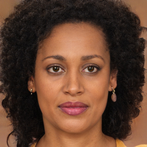 Joyful black adult female with long  brown hair and brown eyes