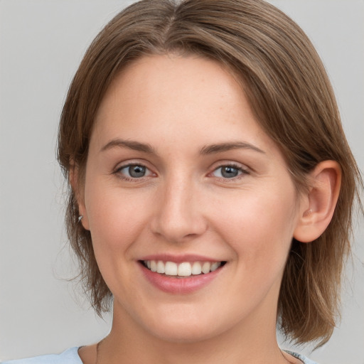 Joyful white young-adult female with medium  brown hair and grey eyes