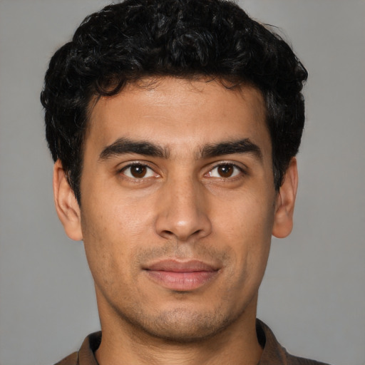 Joyful latino young-adult male with short  black hair and brown eyes