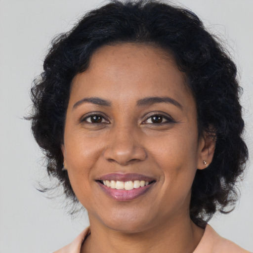 Joyful black young-adult female with long  brown hair and brown eyes