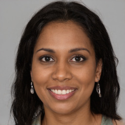 Joyful black young-adult female with long  brown hair and brown eyes