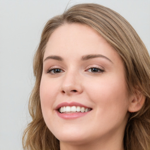 Joyful white young-adult female with long  brown hair and blue eyes