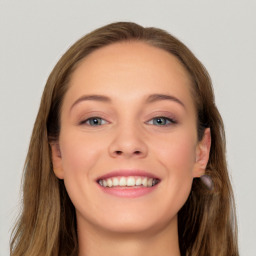 Joyful white young-adult female with long  brown hair and blue eyes