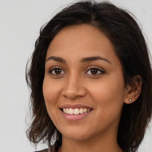 Joyful latino young-adult female with long  brown hair and brown eyes