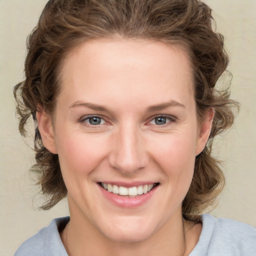 Joyful white young-adult female with medium  brown hair and grey eyes