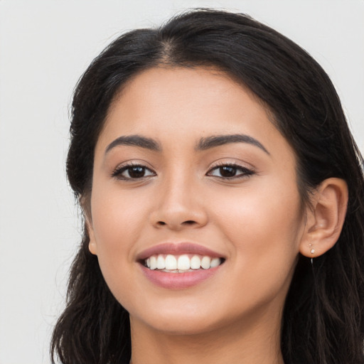 Joyful latino young-adult female with long  black hair and brown eyes