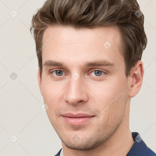 Joyful white young-adult male with short  brown hair and grey eyes