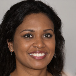 Joyful black young-adult female with long  brown hair and brown eyes