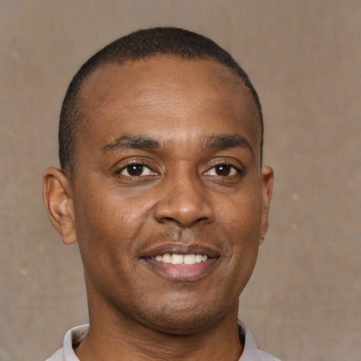 Joyful black young-adult male with short  brown hair and brown eyes