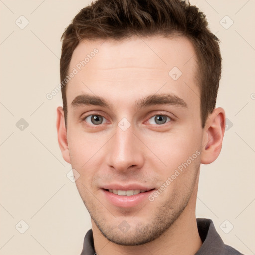 Joyful white young-adult male with short  brown hair and grey eyes