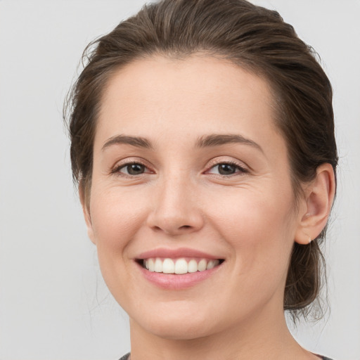 Joyful white young-adult female with medium  brown hair and grey eyes