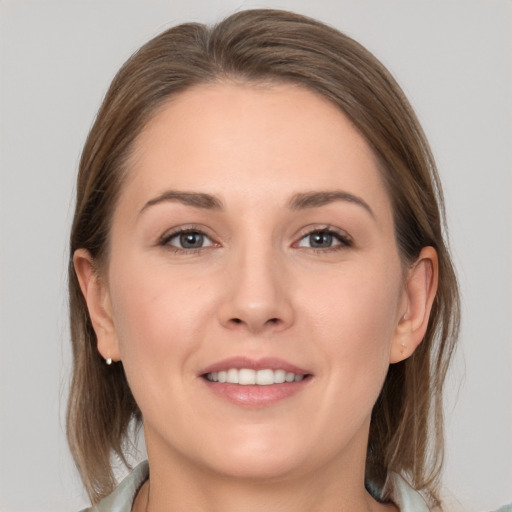 Joyful white young-adult female with medium  brown hair and grey eyes