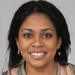 Joyful black young-adult female with long  brown hair and brown eyes