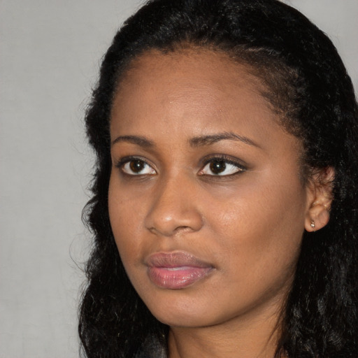 Joyful black young-adult female with long  brown hair and brown eyes