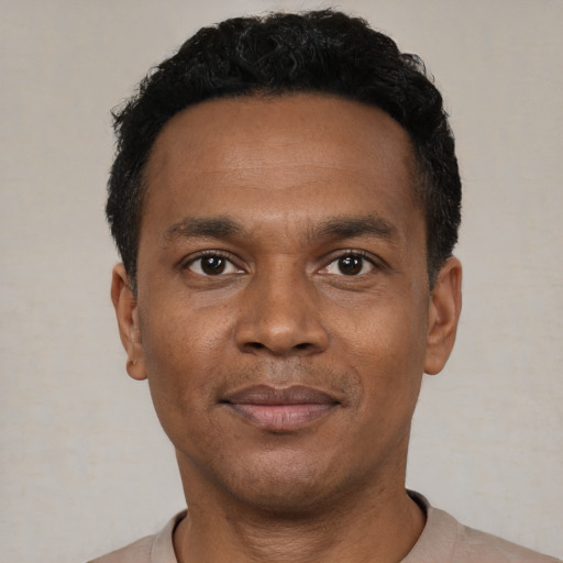 Joyful black young-adult male with short  black hair and brown eyes