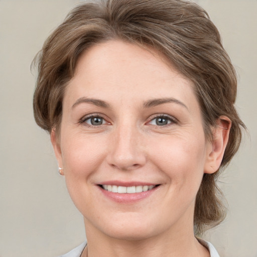 Joyful white young-adult female with medium  brown hair and grey eyes