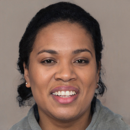 Joyful black young-adult female with long  black hair and brown eyes