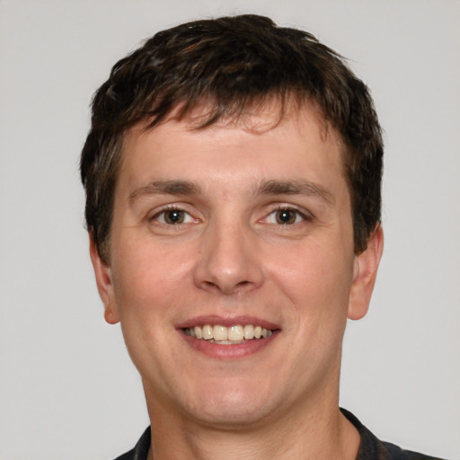 Joyful white young-adult male with short  brown hair and grey eyes