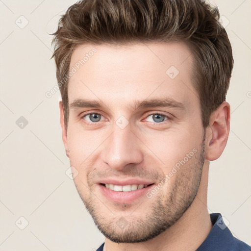 Joyful white young-adult male with short  brown hair and grey eyes