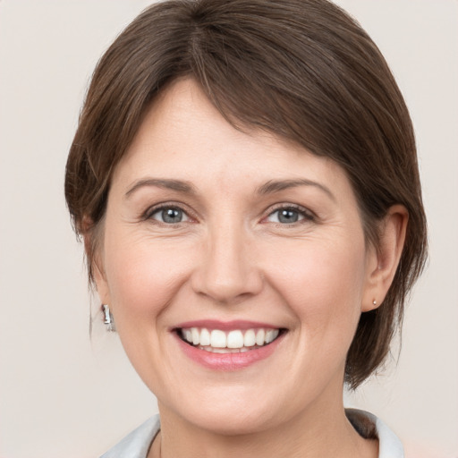 Joyful white young-adult female with medium  brown hair and grey eyes