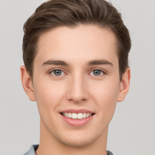 Joyful white young-adult male with short  brown hair and grey eyes