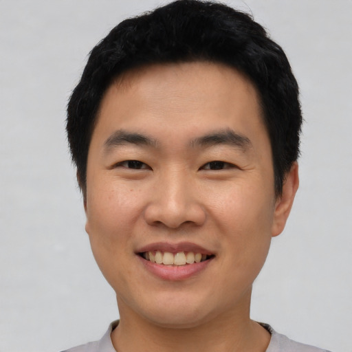 Joyful asian young-adult male with short  black hair and brown eyes