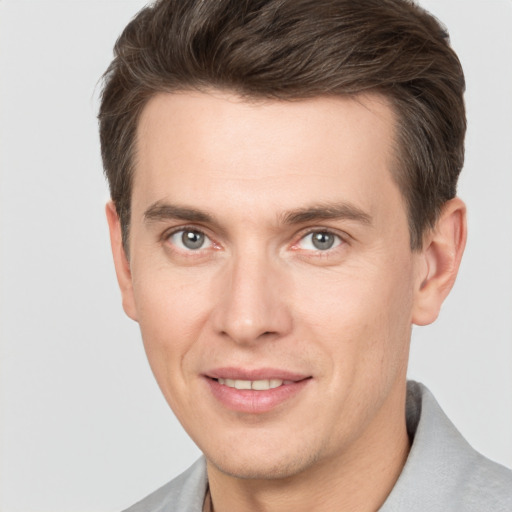 Joyful white young-adult male with short  brown hair and grey eyes