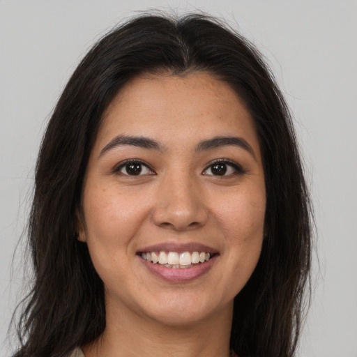 Joyful latino young-adult female with long  brown hair and brown eyes